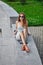 Young attractive stylish woman sitting on marble surface with bent knee