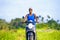 Young attractive tourist afro American black woman riding motorbike happy in beautiful Asia countryside along green rice fields s