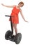 Young attractive tourist woman in chic summer dress smiling happy hands free riding electrical segway