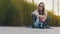 Young attractive woman adjusting roller blades while sitting in the park.