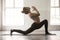 Young attractive woman in anjaneyasana pose, white loft studio b