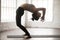 Young attractive woman in Ardha Chakrasana pose, white loft stud