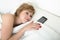 Young attractive woman in bed alone with mobile phone as sleeping partner in internet and smart phone addiction concept