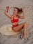 Young attractive woman in bikini with straw hat sit and makes selfie at sandy beach. Happy girl at vacation