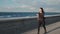 Young attractive woman in black sportswear runs down the sea coast slow motion