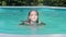 A young, attractive woman in a black swimsuit swims in the pool. Rest in the water in hot summer weather