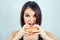 Young and attractive woman in black T-shirt and measuring tape eating a high-calorie burger