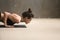 Young attractive woman in chaturanga dandasana pose, grey studio