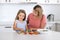 Young attractive woman cooking together with her sweet beautiful blond little 6 or 7 years old daughter smiling happy preparing sa