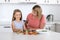 Young attractive woman cooking together with her sweet beautiful blond little 6 or 7 years old daughter smiling happy preparing sa
