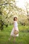 Young attractive woman with curly hair walking in a green flowered garden. Spring mood