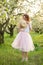 Young attractive woman with curly hair walking in a green flowered garden. Spring mood