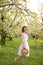 Young attractive woman with curly hair walking in a green flowered garden. Spring mood