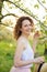 Young attractive woman with curly hair walking in a green flowered garden. Spring mood