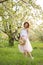 Young attractive woman with curly hair walking in a green flowered garden. Spring mood