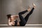 Young attractive woman doing bicycle crunches, grey studio backg