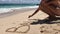 Young attractive woman drawing text Bali on the sand. Tropical beach. Bali island, Indonesia.