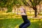 Young attractive woman dressed in sports uniform doing squat plank with dumbbells in hands. Sports activities in the park.