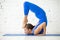 Young attractive woman in Ganda Bherundasana pose, white studio