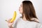 Young attractive woman holding banana like a gun in her hand looking decisive standing on isolated white background dietology and