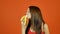 Young Attractive Woman Holding in Hand Yellow Banana and Then Eating it on Bright Orange Background. Tropical Fruits