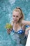 Young attractive woman with long hair in a swimwear in the pool with cocktail in coconut