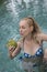 The young attractive woman with long hair in a swimwear in the pool with cocktail in coconut