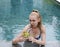 Young attractive woman with long hair in a swimwear in the pool with cocktail in coconut