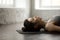 Young attractive woman lying in Corpse pose, white loft studio