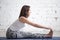 Young attractive woman in paschimottanasana pose, white studio