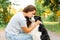 Young attractive woman playing with cute puppy dog border collie on summer outdoor background. Girl kissing holding