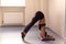 Young attractive woman practicing yoga near window. Adho Mukha V