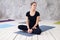 Young attractive woman practicing yoga, sitting in Ardha Padmasana exercise, Half Lotus pose, working out, wearing black