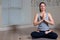 Young attractive woman practicing yoga, sitting, wearing sportswear, meditation session, home interior