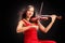 Young attractive woman in red dress playing the violin