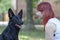 Young attractive woman with red hair and big black dog look to each other. Shepherd with clever impressive eyes.