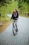 A young, attractive woman rides a white bike in the evening in an autumn park.