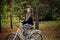 A young, attractive woman rides a white bike in the evening in an autumn park.