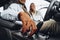 Young attractive woman salesperson in car showroom showing a car to her male client