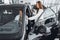 Young attractive woman salesperson in car showroom showing a car to her male client