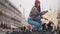 Young attractive woman squats in the square on the background of church and throws bread at a flock of pigeons