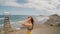 Young attractive woman standing on the coast by the sea in windy day. Place for kitesurfing on a background