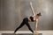 Young attractive woman standing in Utthita Trikonasana pose with