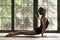 Young attractive woman in upward facing dog pose, window backgro