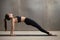 Young attractive woman in Upward Plank pose, grey studio backgro