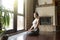 Young attractive woman in vajrasana pose, home interior backgrou