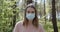 Young attractive woman wearing protective facial mask in the forest