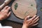 Young attractive woman in white shirt ceramic artist decorating clay plate with dry leaves at the table in pottery workshop.