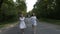 Young attractive women dressed in white running bare foot on a forest country road holding hands -
