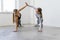 Young attractive women practicing yoga together giving high five holding hands and standing in side plank pose on rubber mats at